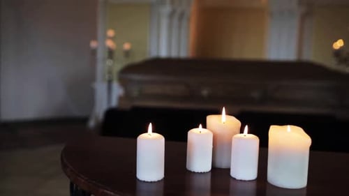 Funeral Burial and Mourning Concept - Burning Candles and Coffin at Church Alight