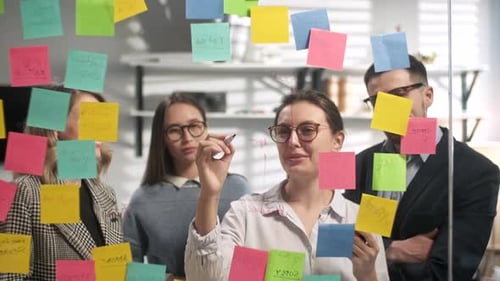 Team Brainstorming Strategy on Glass Whiteboard in Office