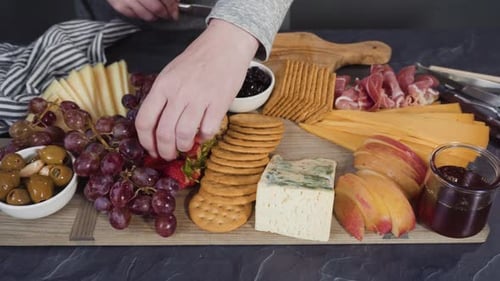 Arranging Gourmet Cheese Crakers and Fruits on a Board for a Large Cheese Board
