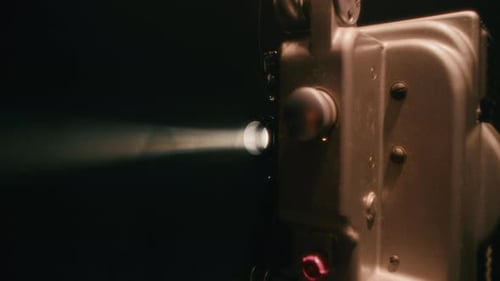 Vintage Film Projector Shining Light in Dark Room
