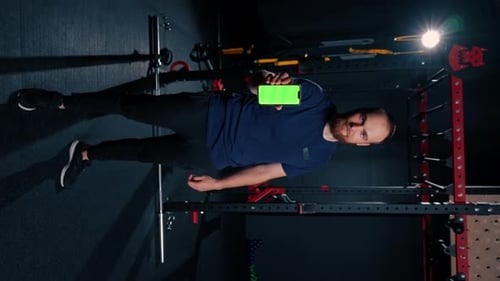 vertical video man fitness trainer shows phone with green screen sport lifestyle training technology