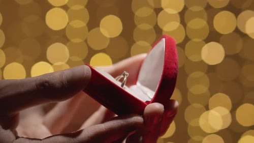 Hands Open Ring Box Under Golden Lights