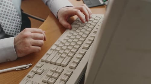 Unrecognizable Clerical Worker Typing on Old Keyboard in Retro Computer