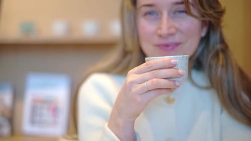 Woman drinking latte art coffee from ceramic cup in a cafe