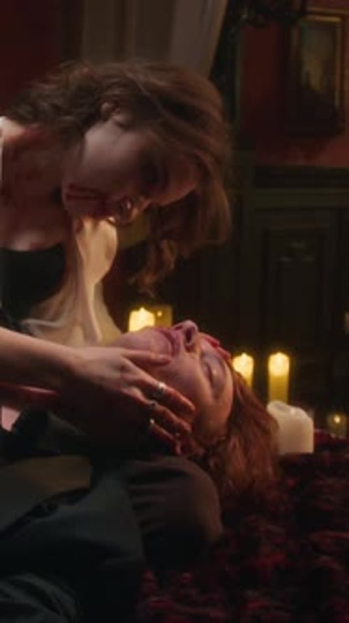 Vampire Woman Gazing Intently at Man Lying Down, her Hands Cradling his Face