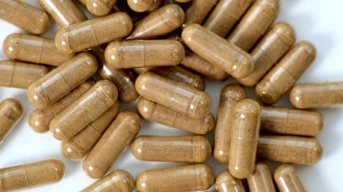 Organic medical pills with herbal plant. Herbal capsules isolated on white background rotating