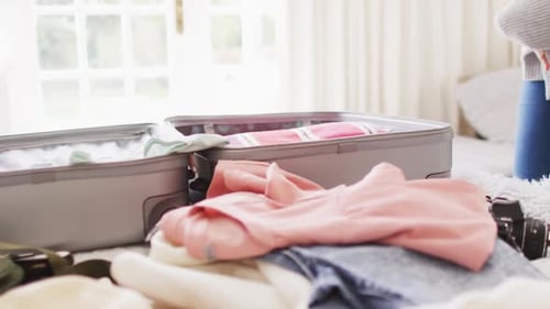 Video of biracial woman packing suitcase