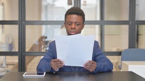 African Businessman Reading Documents in Office