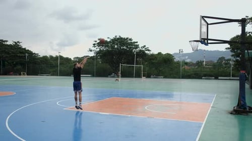 man throws the ball and hits the basket on the basketball court in the park
