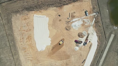 Schwenken Sie aus der Luft (von oben nach unten) über eine aktive Baustelle mit schweren Lastwagen bei der Arbeit