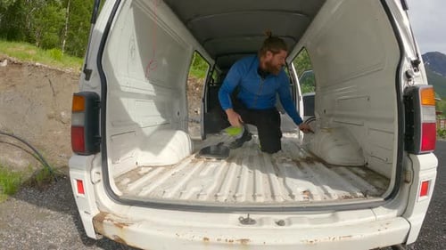 Hombre barbudo limpiando una autocaravana, después de un tratamiento de oxidación, furgoneta construye una vieja Mitsubishi L300.