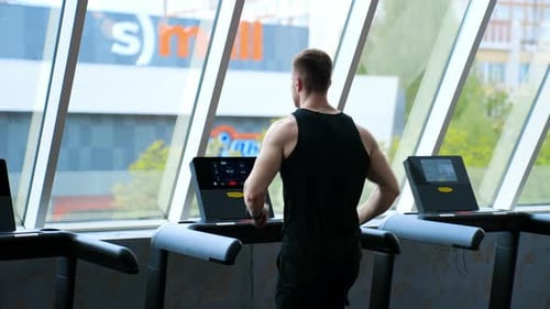 Man training legs in sport club. Young athletic man running on treadmill in sport gym