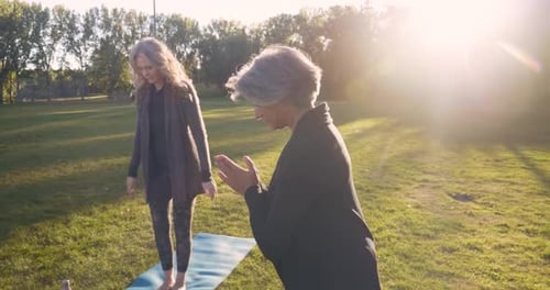 Mature women enjoying sunny yoga session together in peaceful autumn park