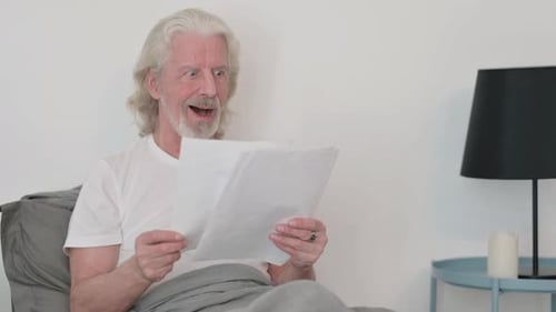 Senior Man Reacting to Positive News in Bed