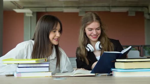 Two Students Doing Homework Together and Helping Each Other Sitting in a Table at University
