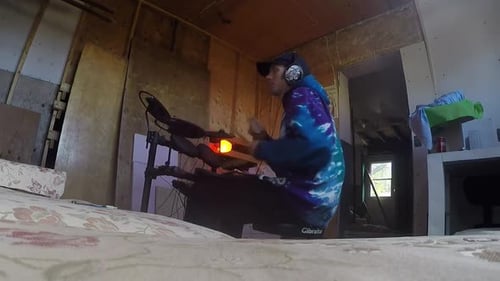 Musician drumming in a warehouse on a electronic drum set.