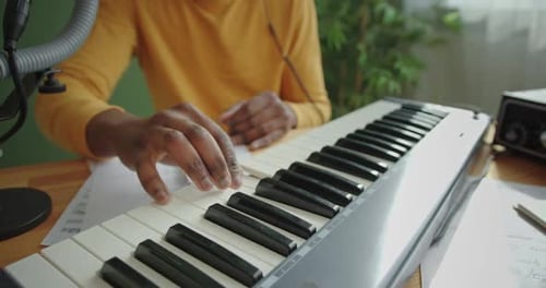 Musician Writing Music at Keyboard in Home Studio