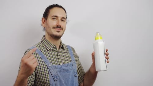 Young Adult Man Points to a Bottle Indoors