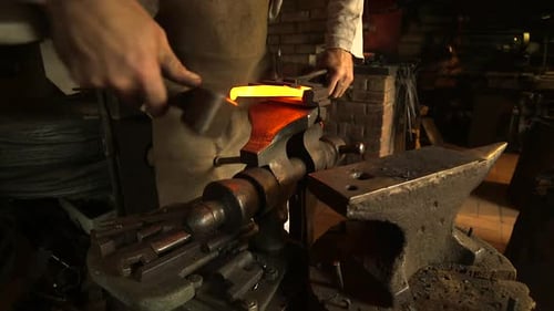Blacksmith Working Metal with Hammer on Anvil