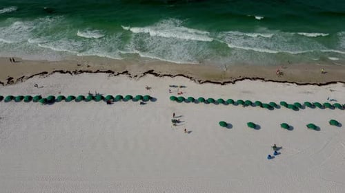 Top down Aerial view of Emerald coast beach green umbrella on a tropical florida white sandy beach i