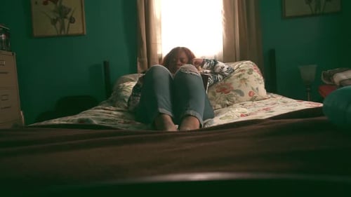 Adult Sitting on a Bed in a Bedroom
