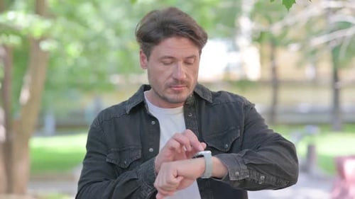 Man Using Smart Watch in Urban Park Setting