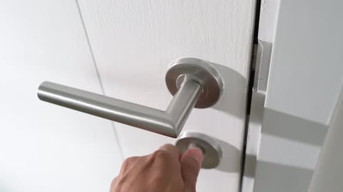 Turning the lock to open the door.