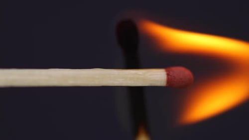 Ignition matches close up macro shot from side view captured in front of black background in slow mo
