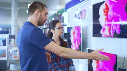 In the Electronics Store Professional Consultant Provides Expert Advice to a Young Woman Who Looks