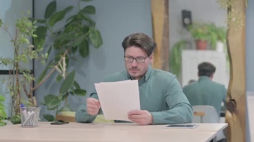 Middle Aged Man Reading Documents in Office