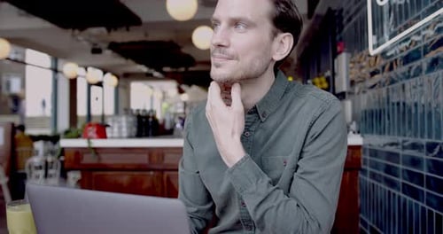 Entrepreneur masculin hipster travaillant sur un ordinateur portable dans le restaurant Trendy Cafe et envisageant