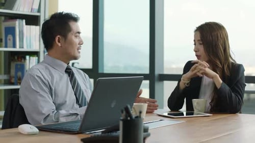 two asian corporate executives meeting in office discussing business using digital tablet