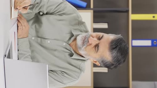 Vertical video of Stressed businessman looking at document.