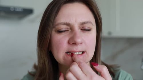 Woman Picking at Tooth in Kitchen Close-Up