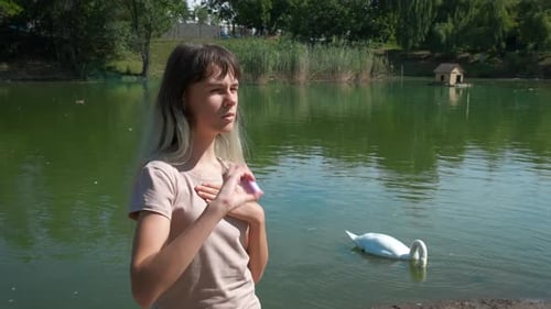 Woman Blows Bubbles by the Lake with Swans