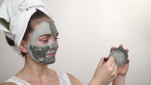 Woman Applies Clay Face Mask with Brush