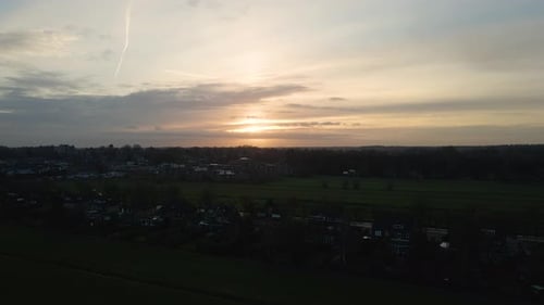 Jib up over row of houses near a small, rural town at sunset