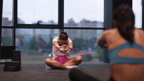 Women Performing Yoga Stretches at an Indoor Gym
