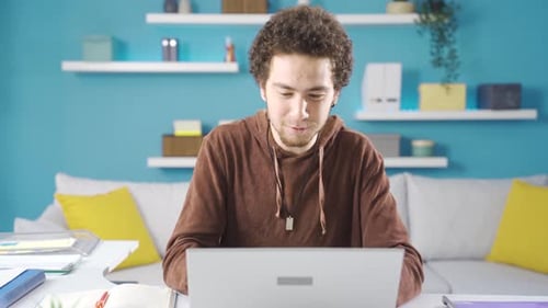 Successful young male student celebrating victory in home office, reading good news.