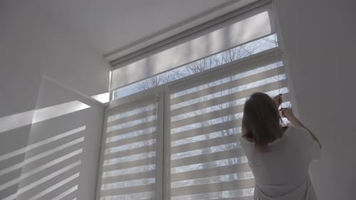 Adult Woman Adjusting Window Blinds in Home
