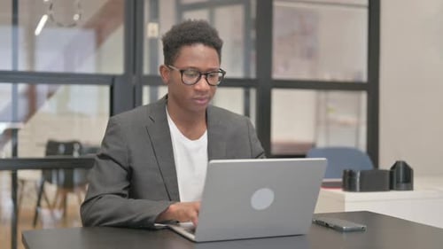 Man Coughing While Using Laptop at Workplace