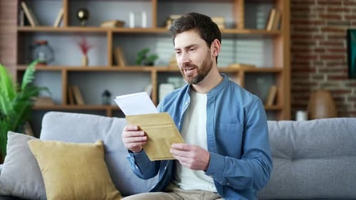 Excited Man Reads Letter on Sofa