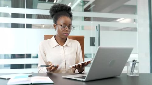 Professional Woman at Computer Taking Notes in Office