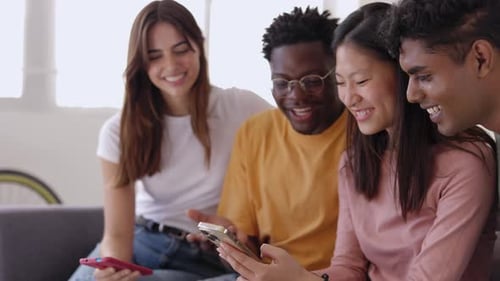 Friends Laughing Together at Smartphone Content Indoors