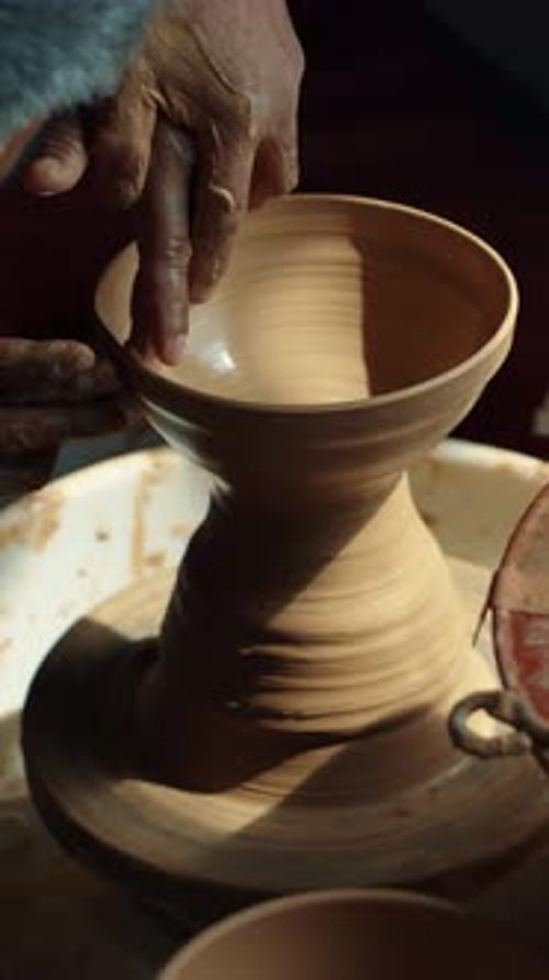 Close-Up of Hands Shaping Clay Vase on Pottery Wheel in Sunlit Studio