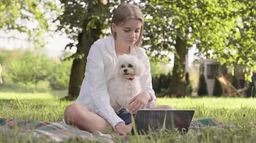 Combining Work and Leisure a Young Woman Sits in the Park with a Laptop Shops Online and Enjoys Time