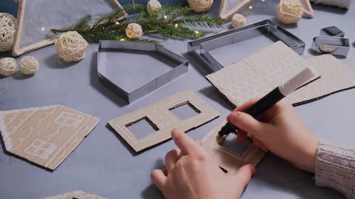 Hand decorating cardboard gingerbread house with marker