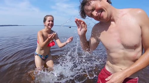 Paar spielt im Wasser. Junges Paar hat Spaß im See, sorgt für Planschen und genießt den Sommertag