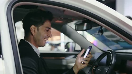 Man Uses Smartphone in Car, Smiling