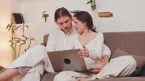 Young Couple Relaxing on Sofa With Laptop